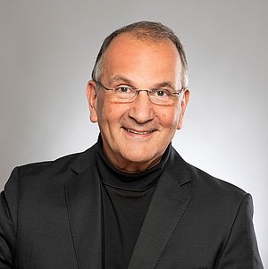 älterer Herr schaut frontal in die Kamera.