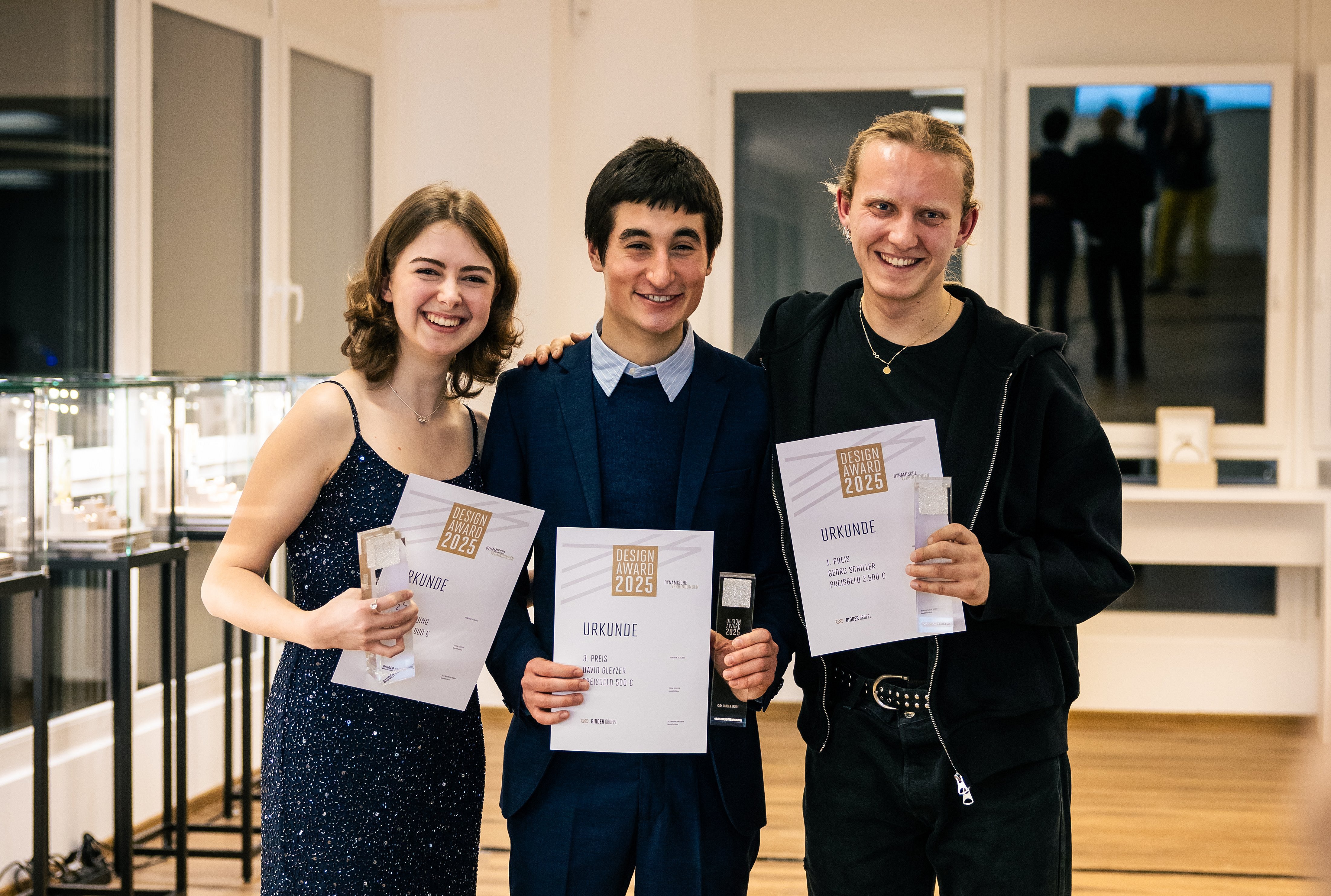 Drei Studierende strahlen mit ihrer Auszeichnung. Sie wurden mit dem Design Award der BINDER Gruppe ausgezeichnet.