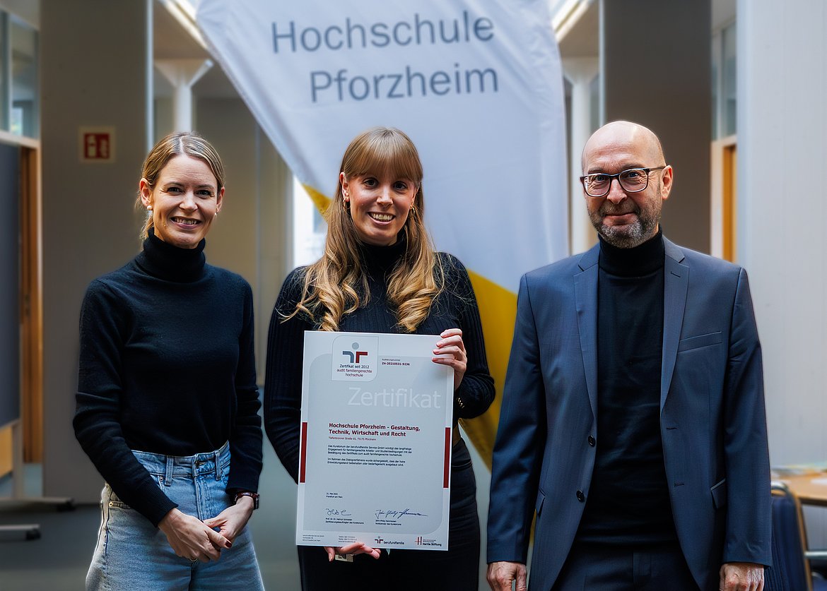 Katrin Plentz, Abteilungsleitung Personalentwicklung, Hochschulkanzler Bernd Welter sowie Personalreferentin Katharina Licht stehen nebeneinander und halten die Urkunde "Familiengerechte Hochschule" ins Bild.