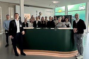 Gruppenfoto von Personen stehend vor und hinter einem Ausstellungsmöbel