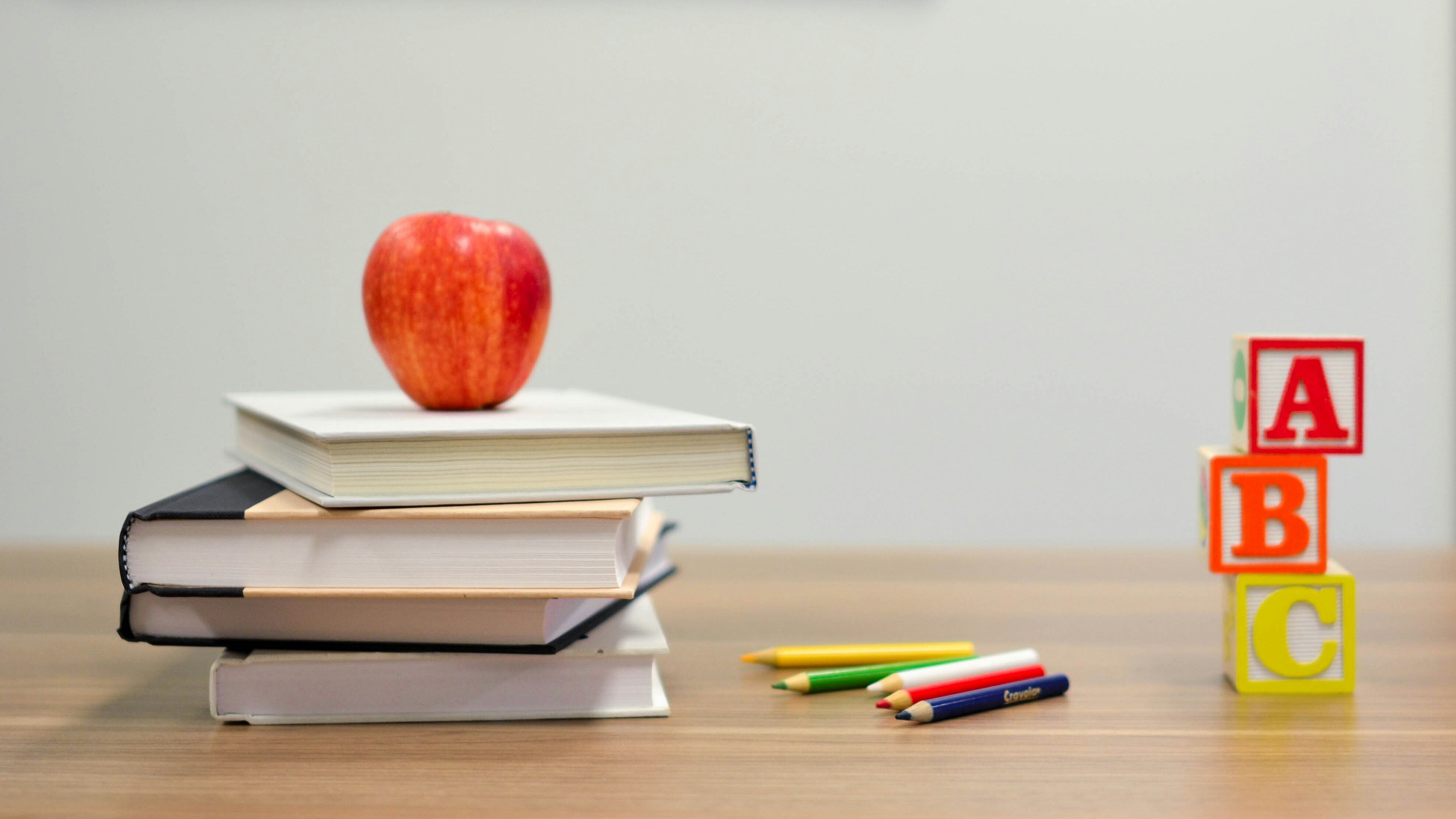 Schreibtisch mit Büchern, einem Apfel und anderem Unterrichtsmaterial