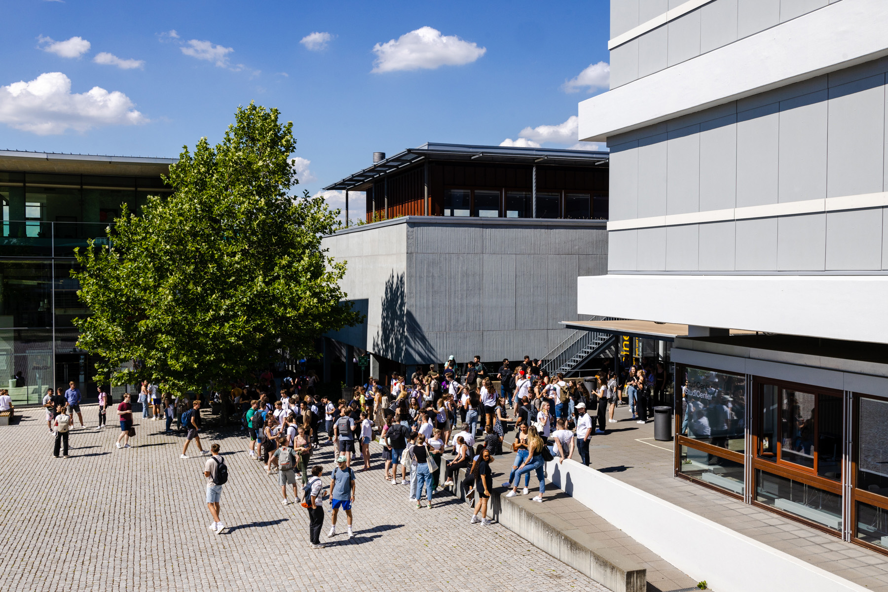 Zu sehen ist die Fakultät Wirtschaft und Recht von außen. Auf dem Campus befinden sich viele Studierende.